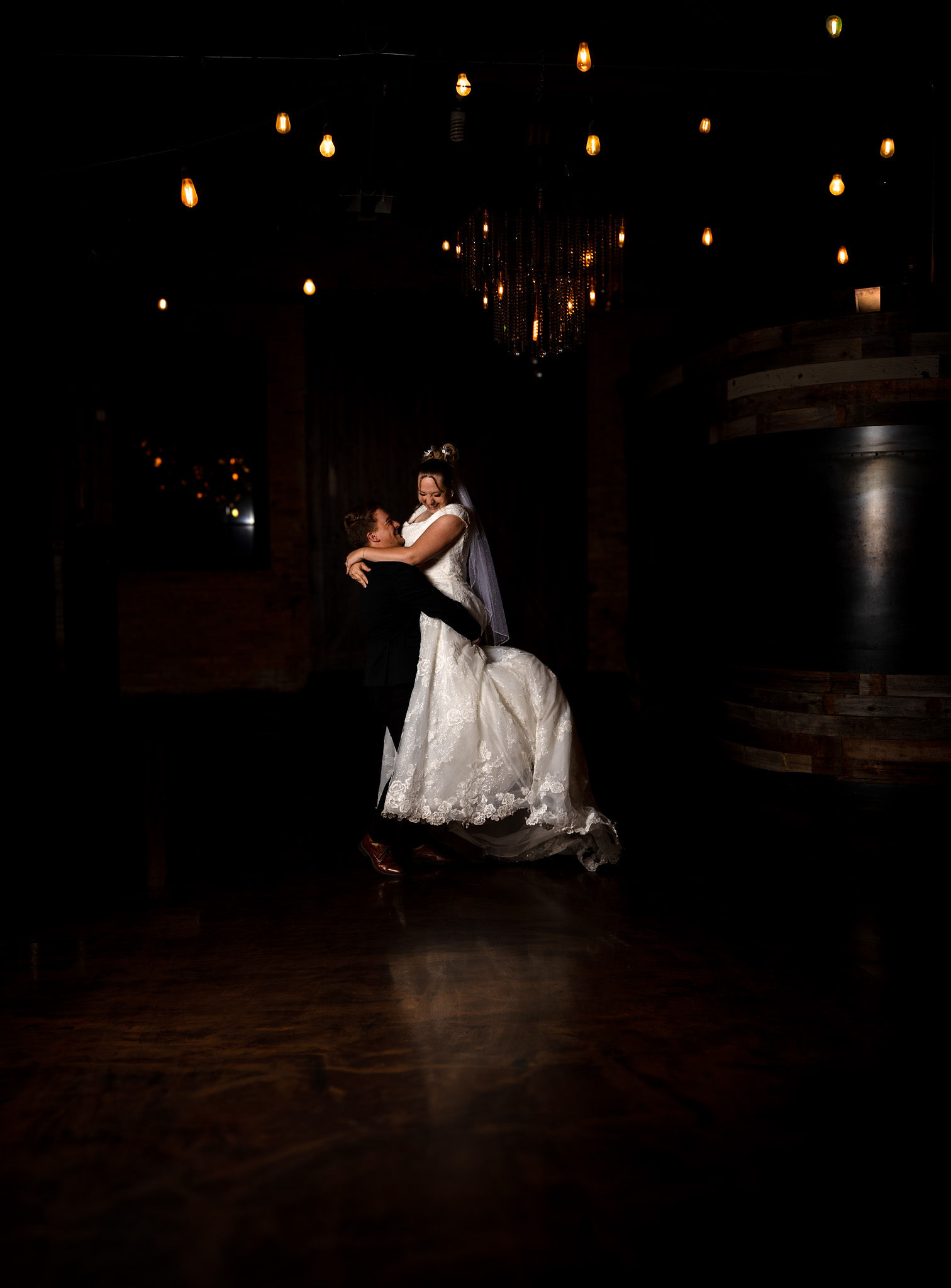Groom lifting bride with "twinkle" lights.
