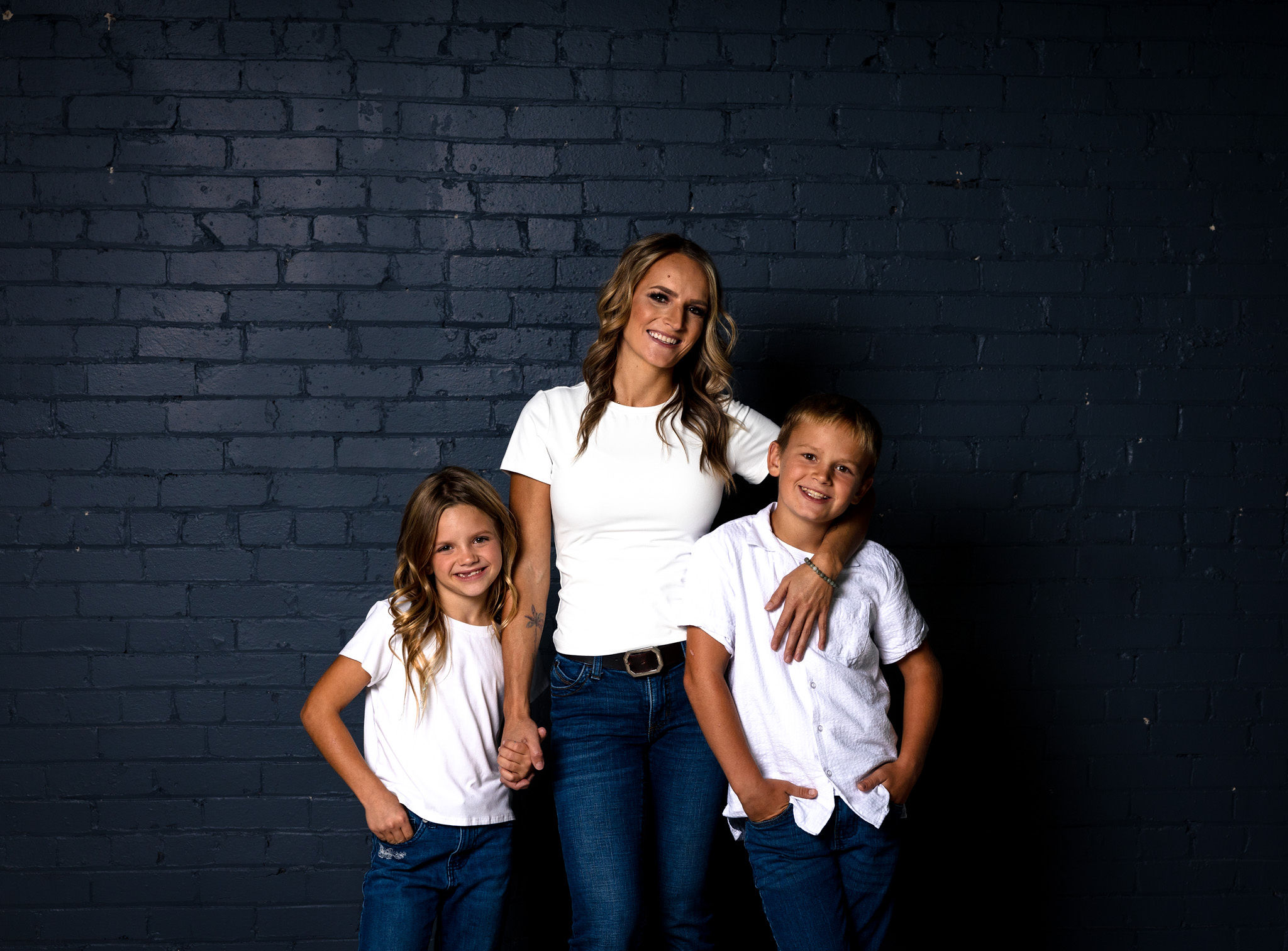 Mom and children on blue wall in jeans.