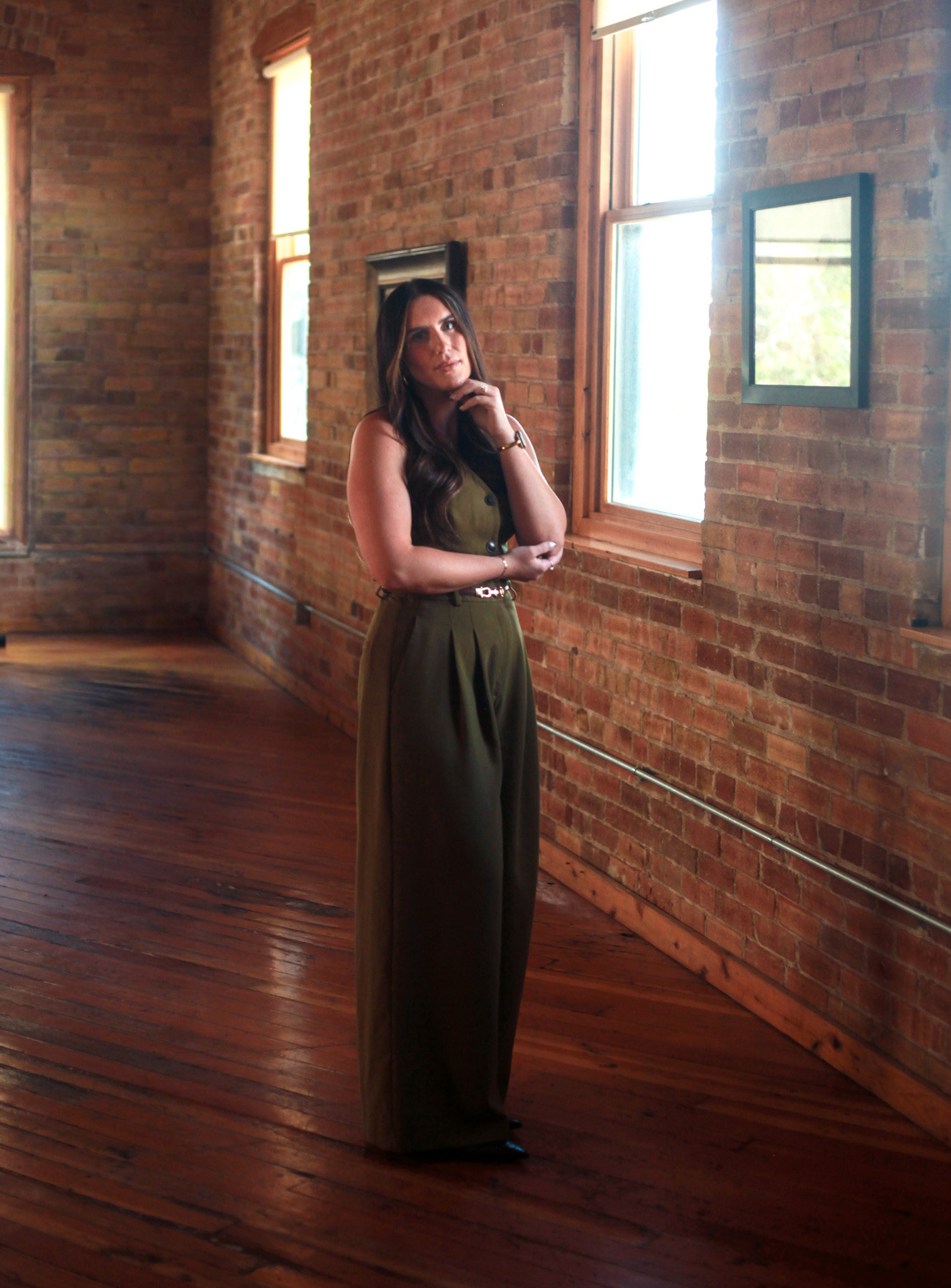 Professional woman standing in brick room.