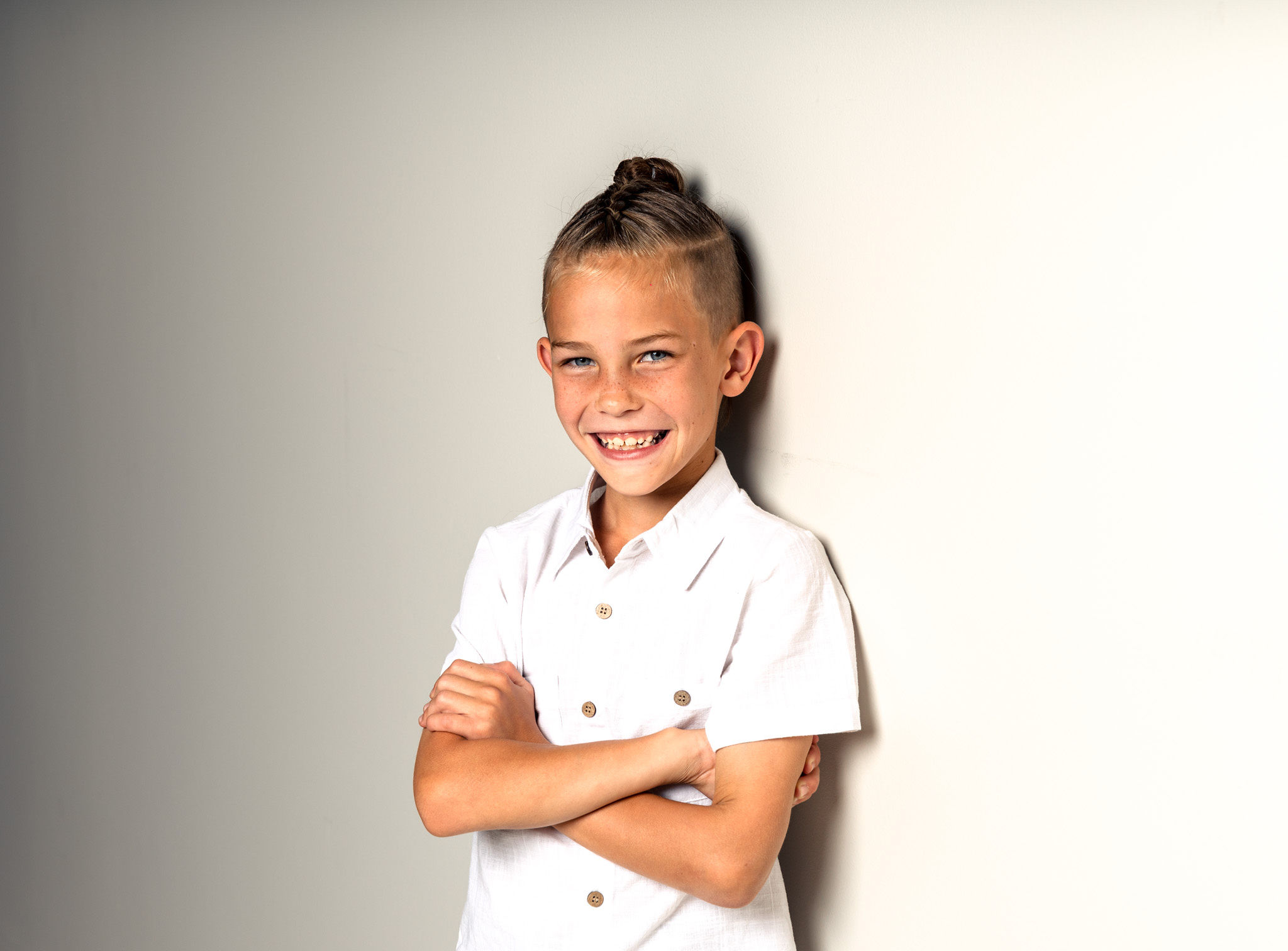Little boy folding arms on white.