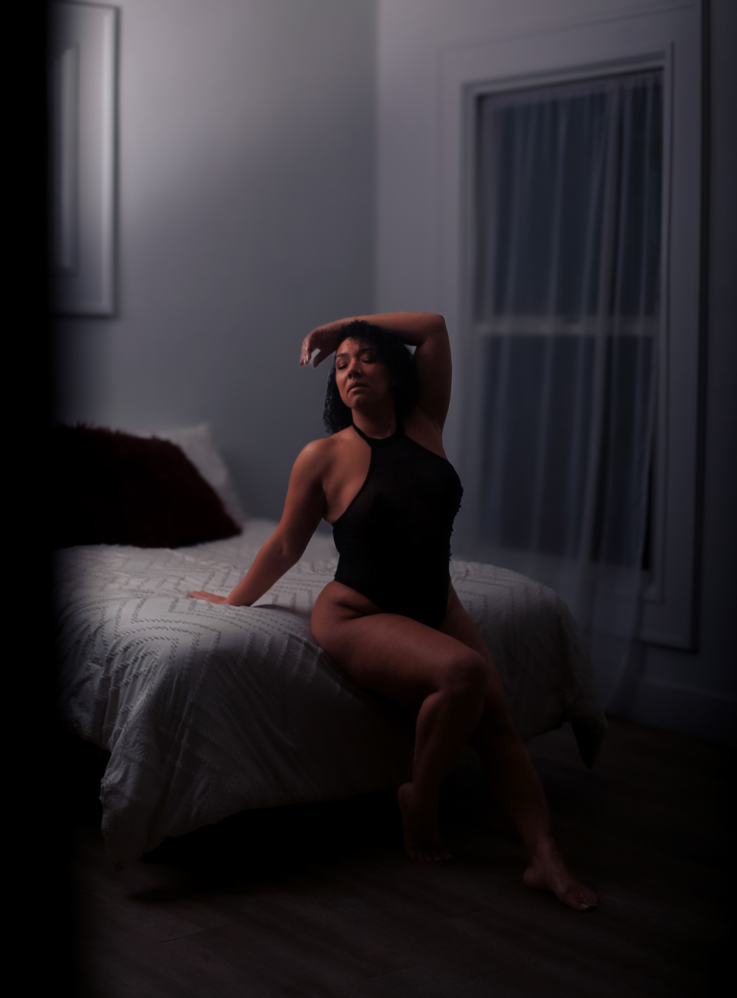 Woman sitting on end of bed.
