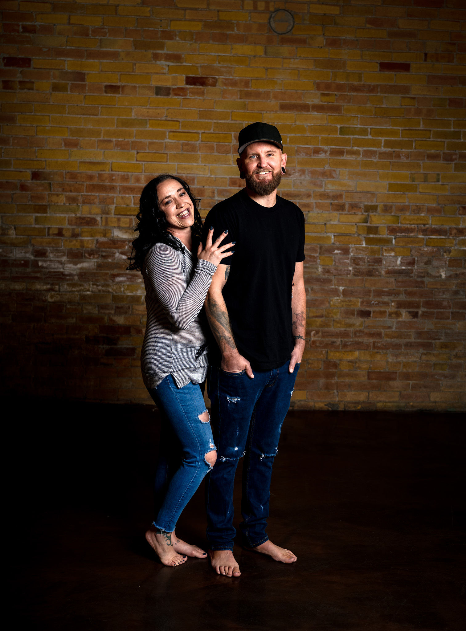 Barefoot couple on brick wall.