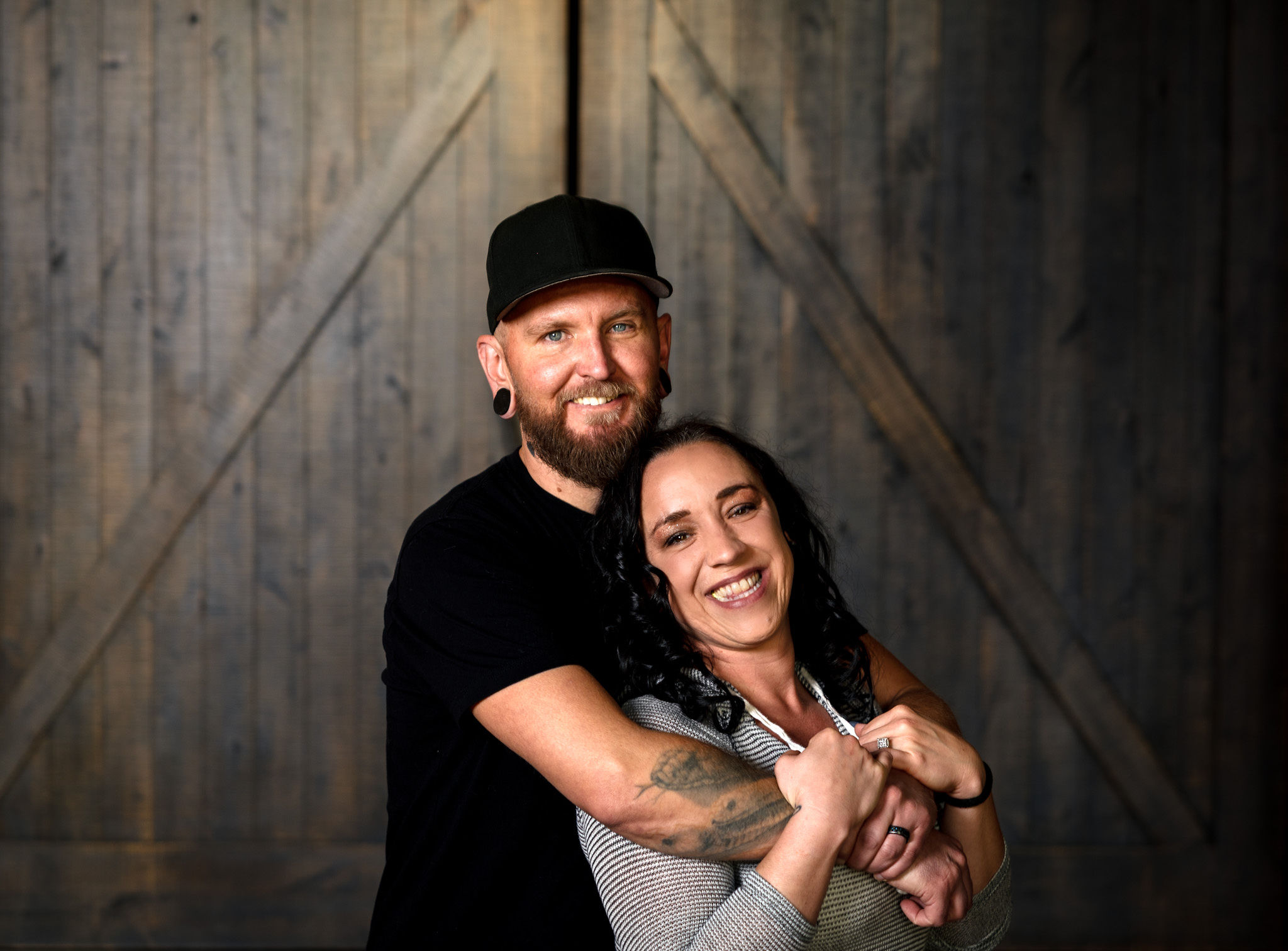 Husband embracing wife from behind with barn doors.
