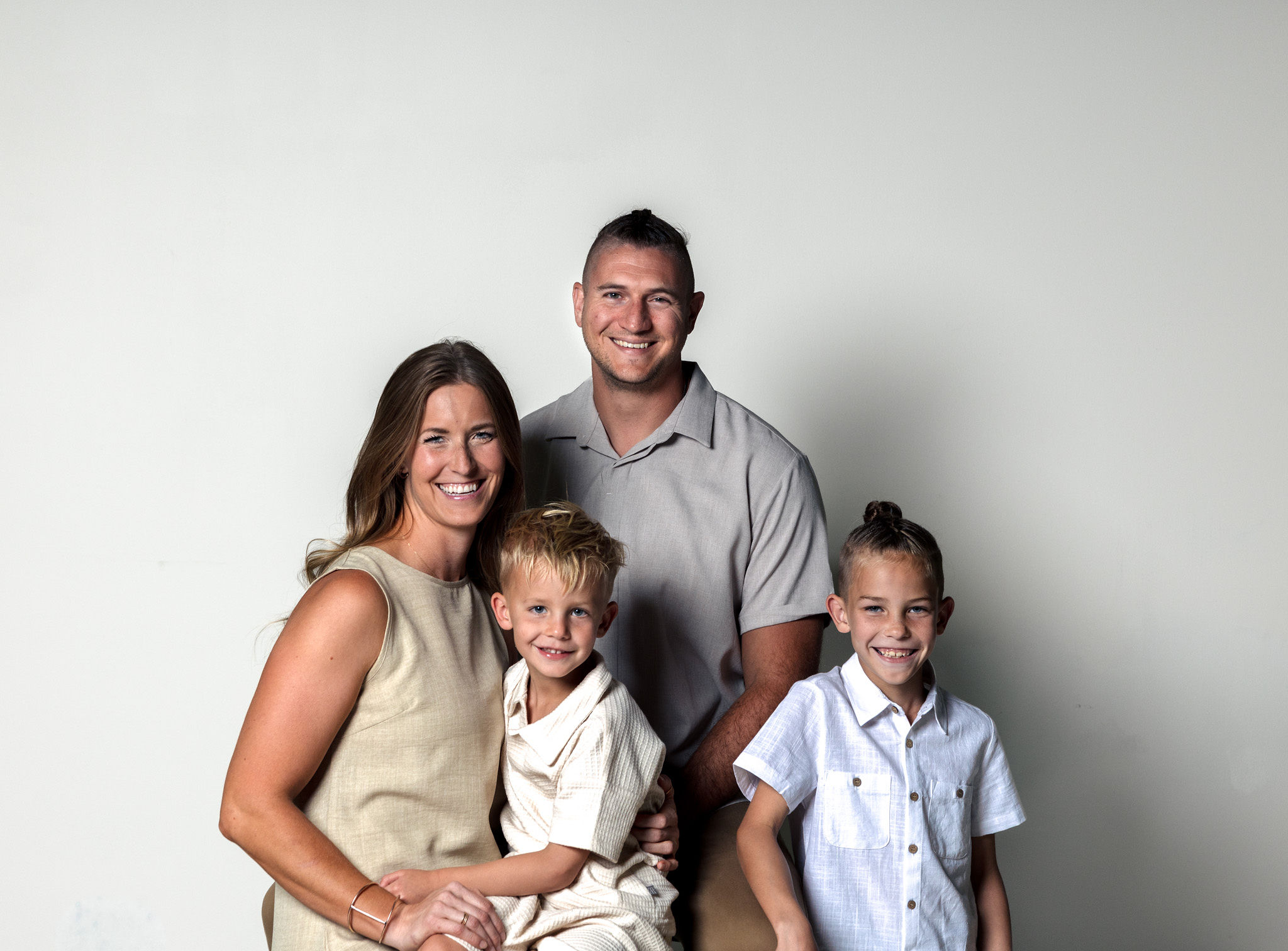 Family of 4 on white wall.