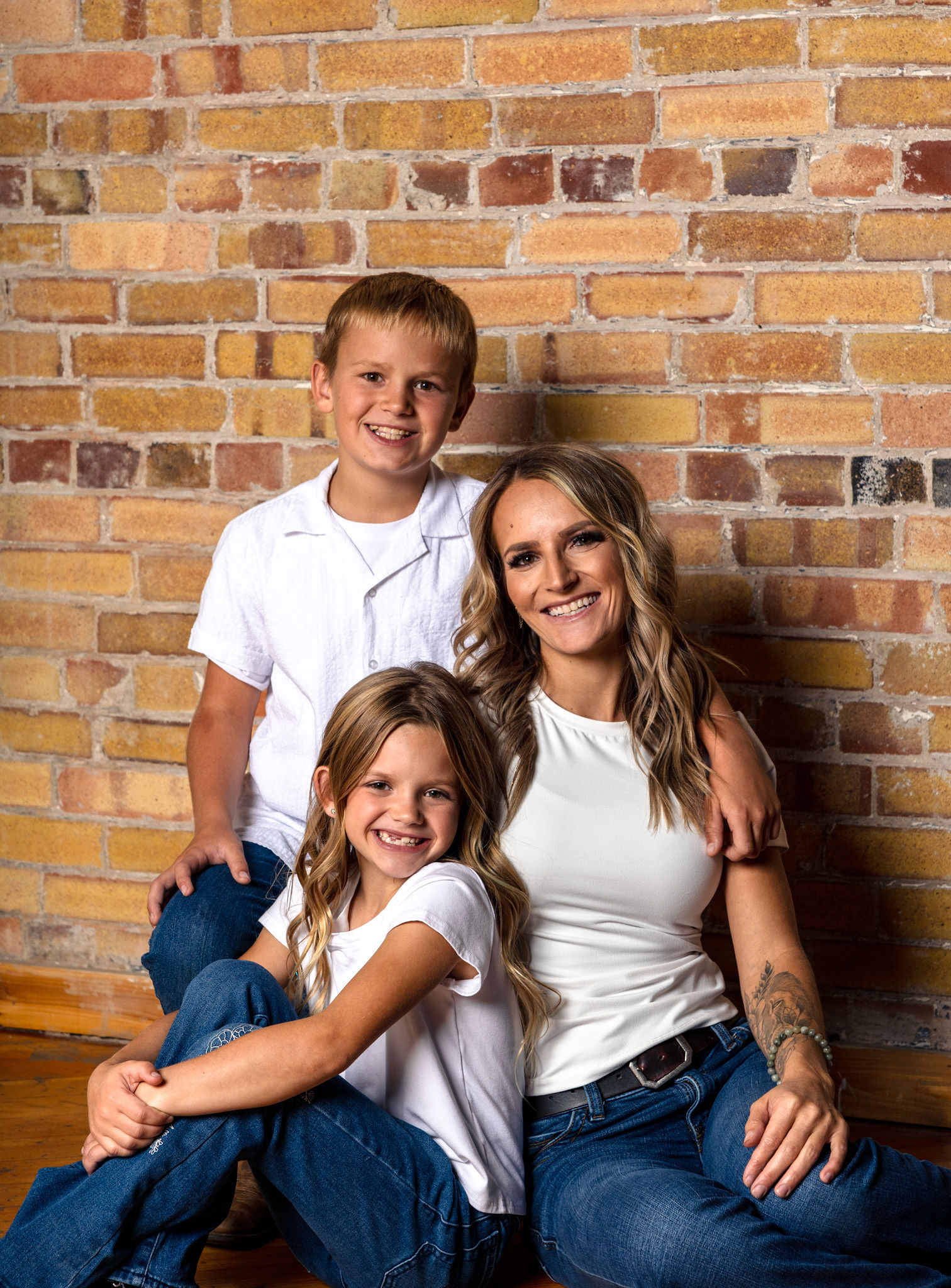 Mom and children sitting against brick.