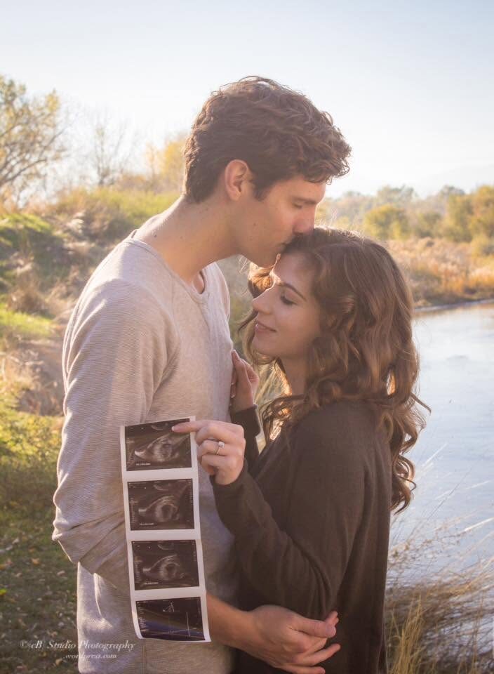 Couple holding a pregnancy ultrasound strip by the riverside