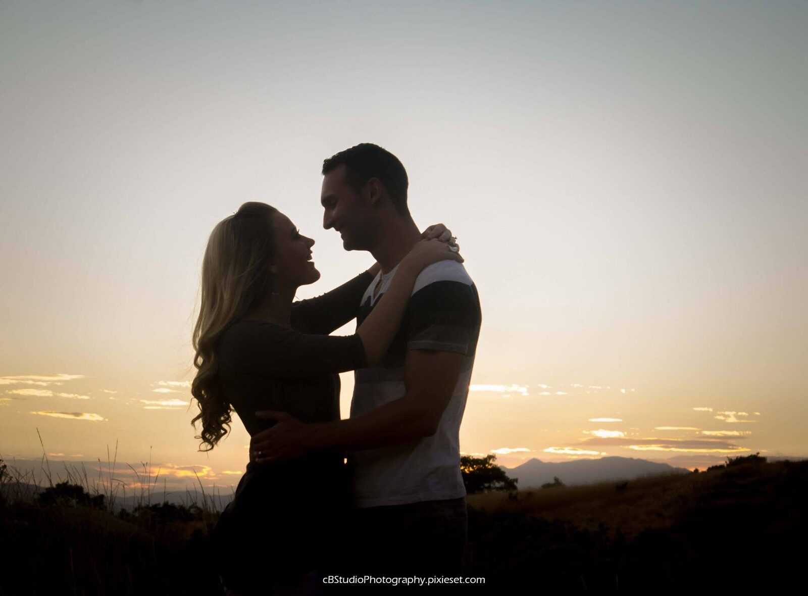 Silhouette of a couple embracing against a mountain sunset