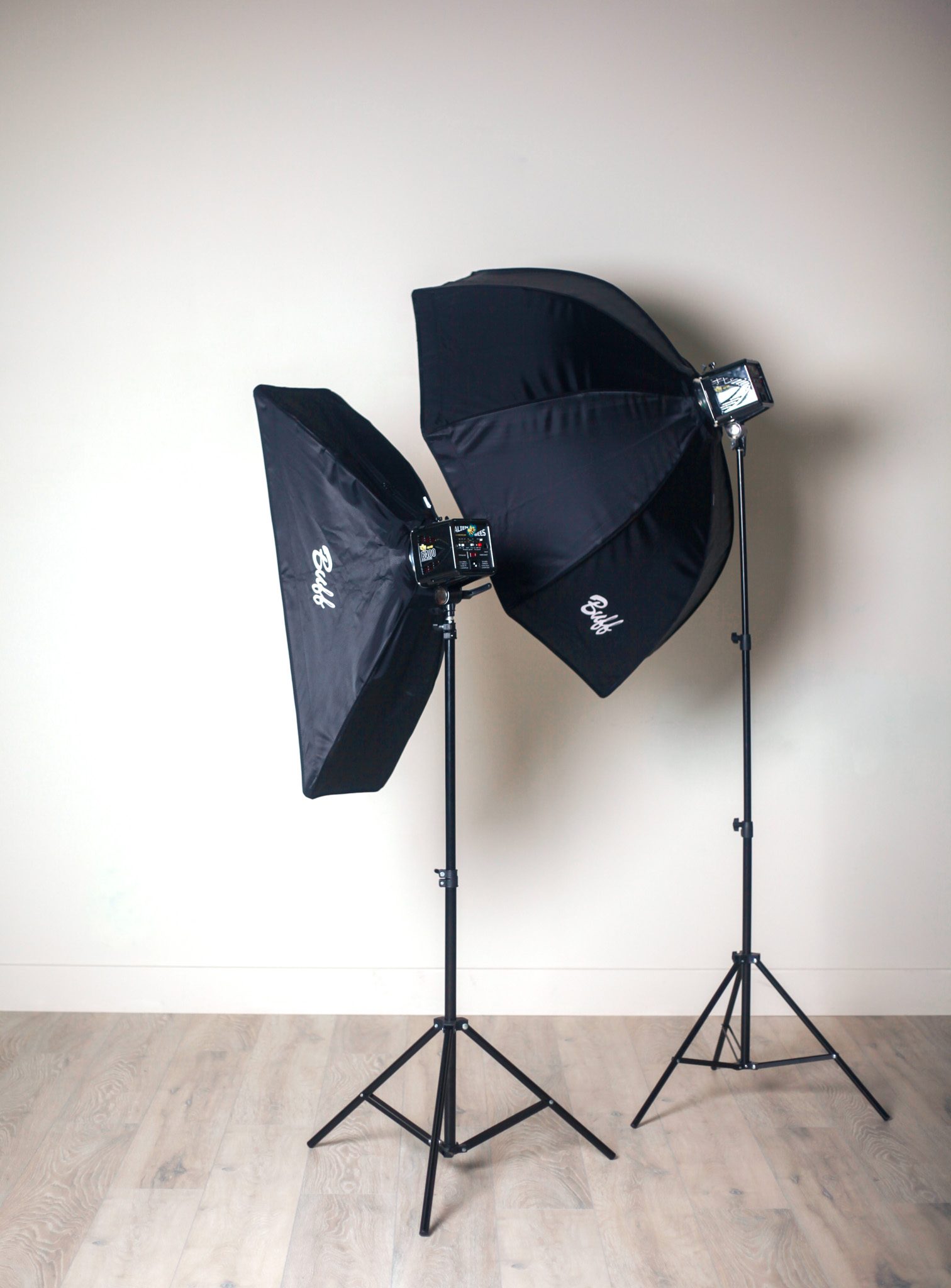 two Paul C. Buff softboxes / strobes on black stands against a light wall and wood floor (no people)